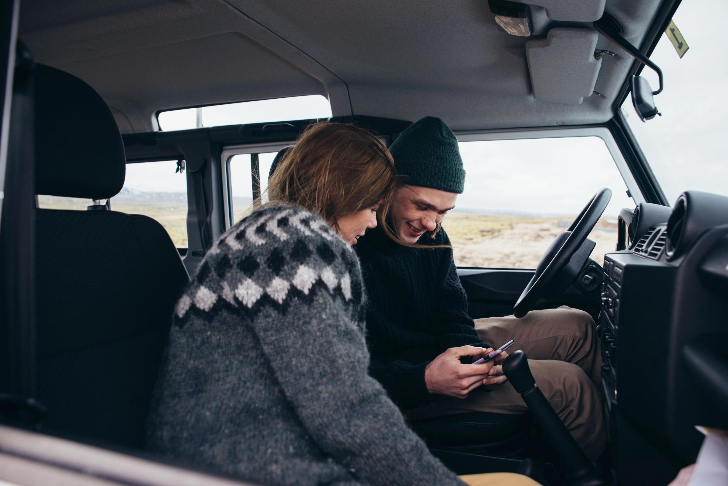 A couple checking their phone on a car rental in Iceland