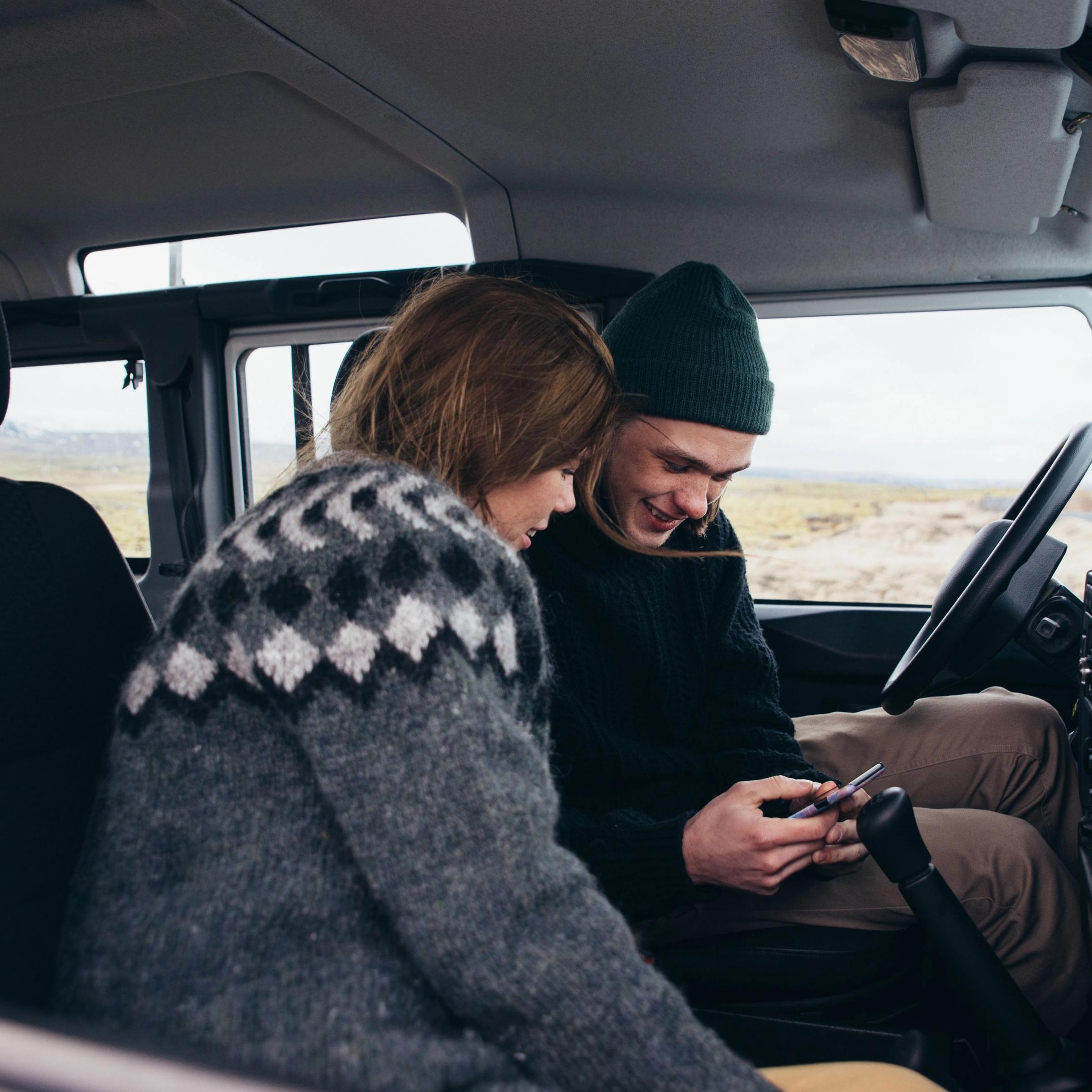 A couple checking their phone on a car rental in Iceland