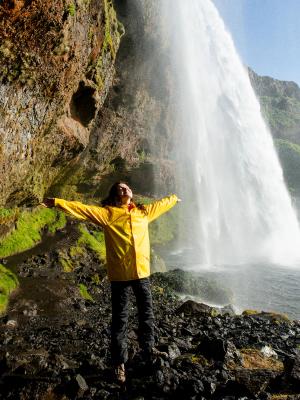 Happy tourist under Seljalandfoss waterfall, Iceland