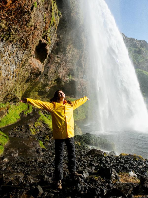Happy tourist under Seljalandfoss waterfall, Iceland