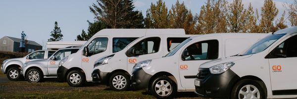 A row of white GO Campers vehicles, including vans and SUVs, parked outdoors.