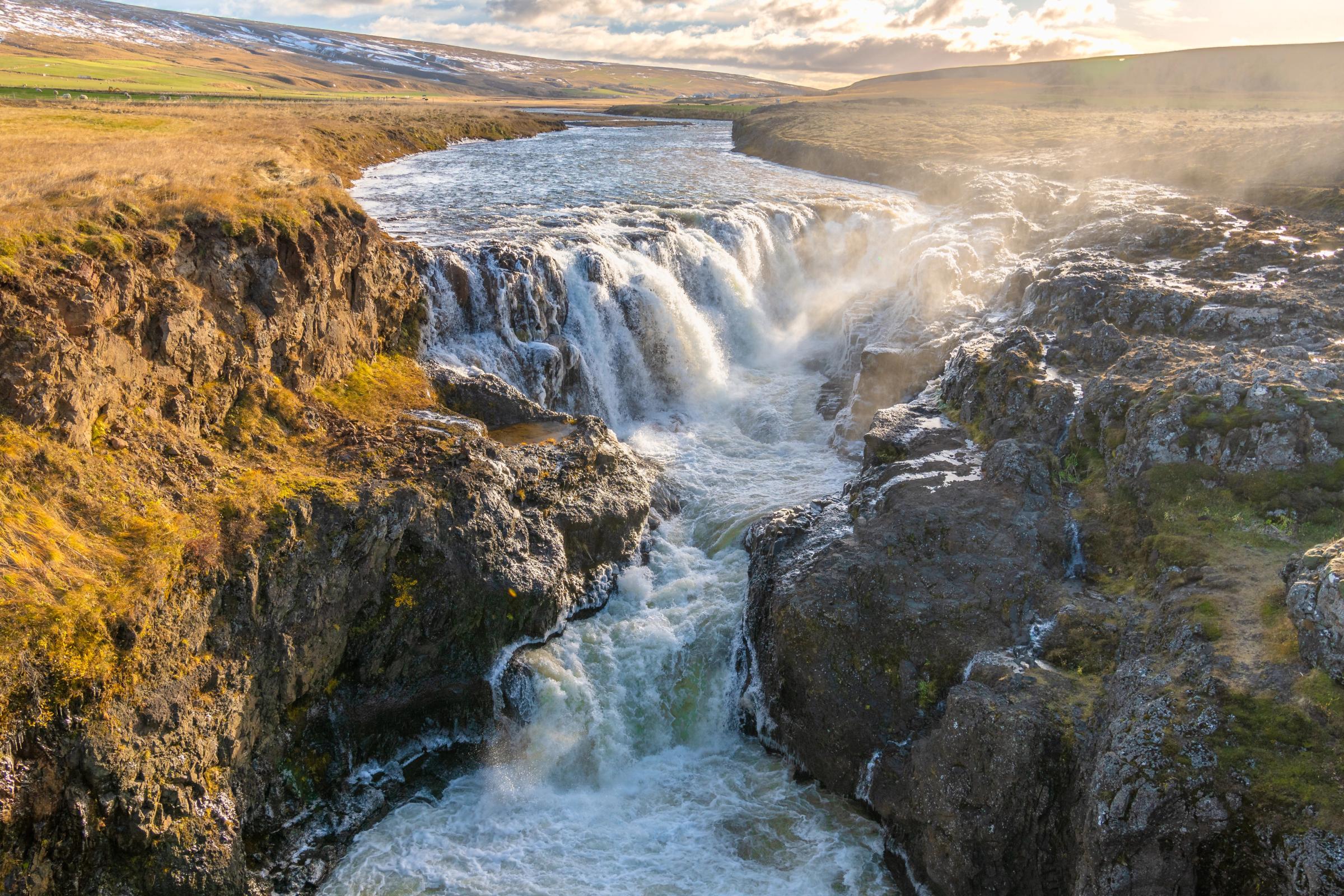 an aerial view of a waterfall in the middle of a canyon .