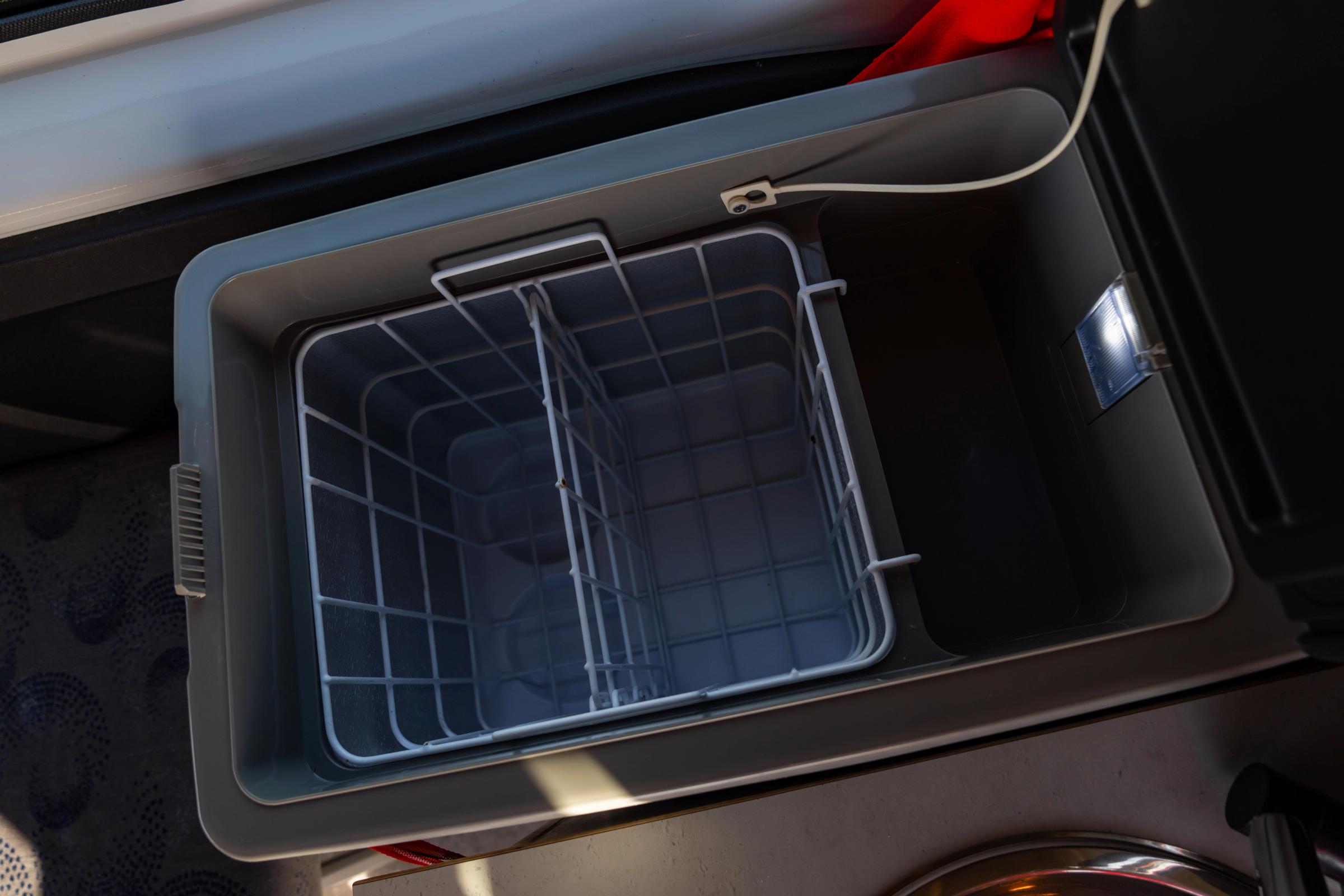 Top down view inside the cool box showing a divided wire basket and interior light
