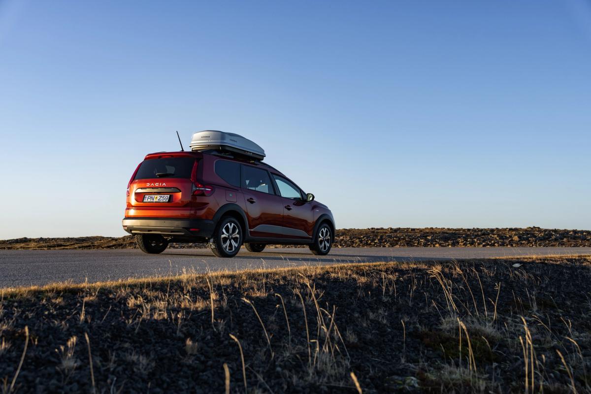 Dacia Jogger rental car in Iceland driving on a paved road with roof box