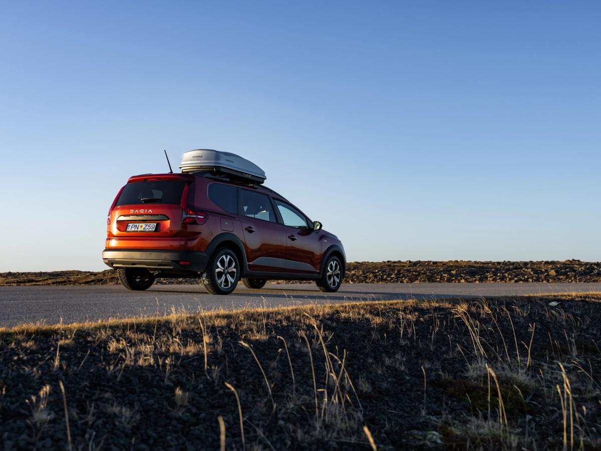 Jogger-Ringstraße Dacia Jogger als Mietwagen in Island mit Dachbox auf einer asphaltierten Straße