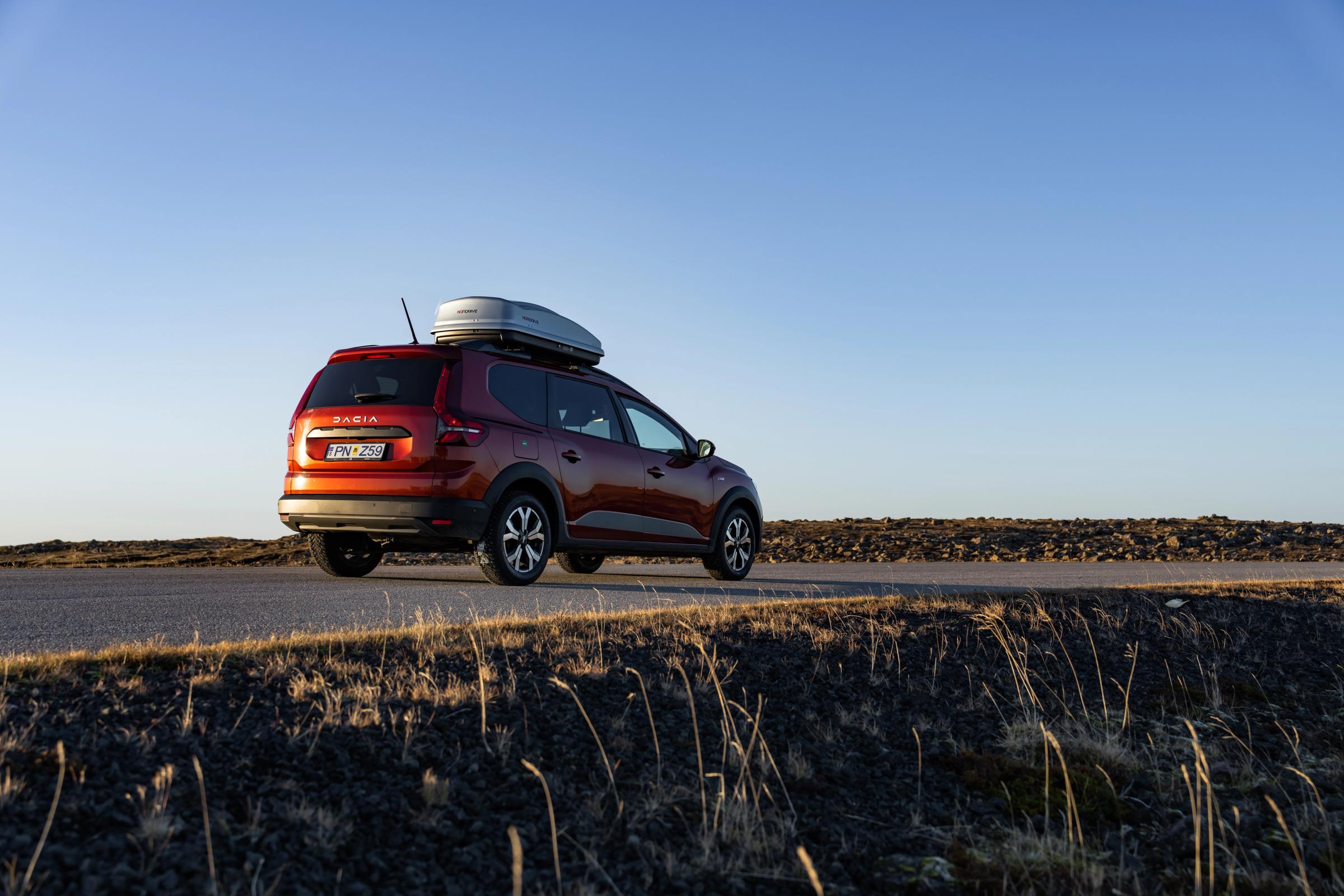 Jogger-Ringstraße Dacia Jogger als Mietwagen in Island mit Dachbox auf einer asphaltierten Straße