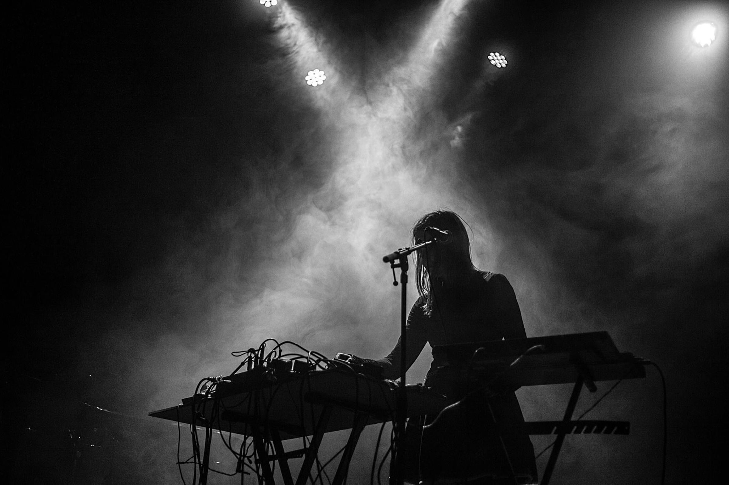 una mujer está tocando un teclado y cantando en un micrófono en un escenario .