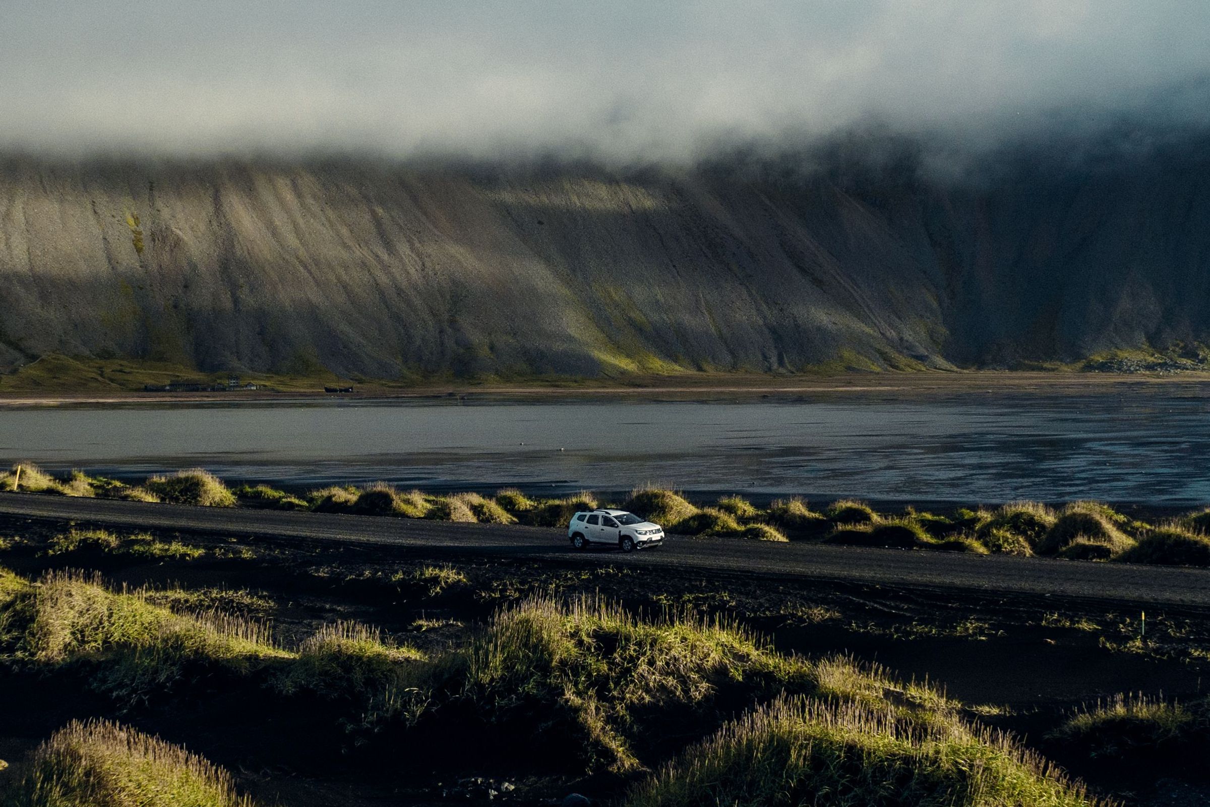 Driving in Iceland rental car on the road in Iceland in the middle of Icelandic landscapes (mountains, green plains and sea)