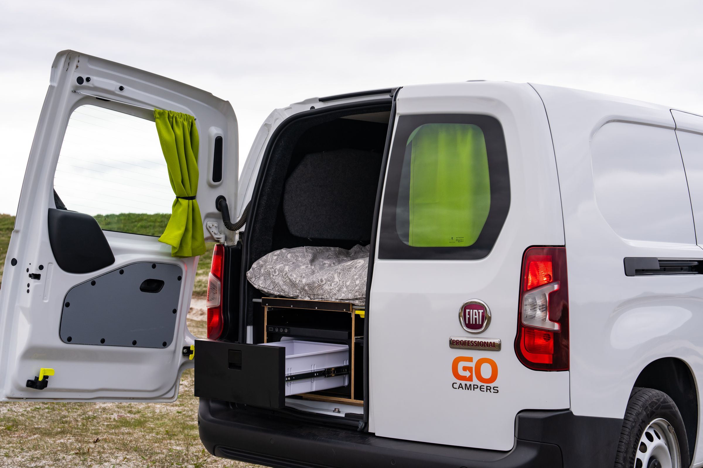 Parte trasera abierta de una autocaravana compacta Parte trasera de una autocaravana compacta con una puerta abierta y el cajón frigorífico extraído debajo de la cama