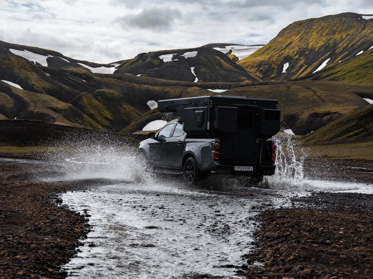 Vista trasera de una autocaravana 4x4 junto al río Una autocaravana 4x4 para 2 personas cruzando un río, vista desde atrás, alquiler de autocaravanas en Islandia