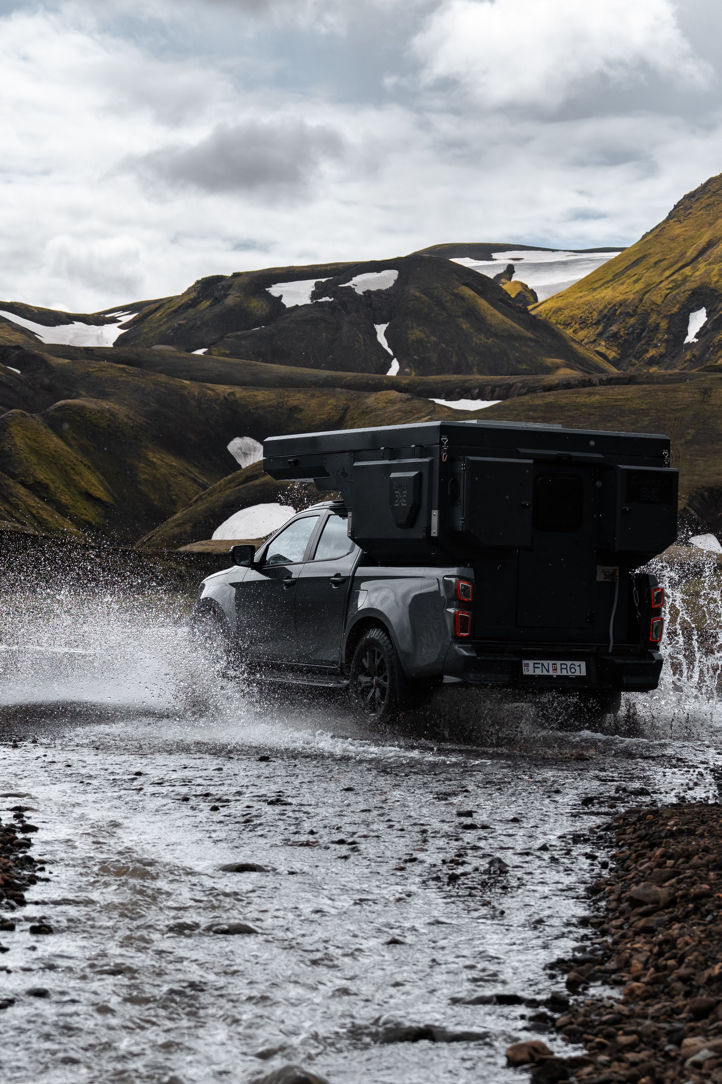 Vista trasera de una autocaravana 4x4 junto al río Una autocaravana 4x4 para 2 personas cruzando un río, vista desde atrás, alquiler de autocaravanas en Islandia