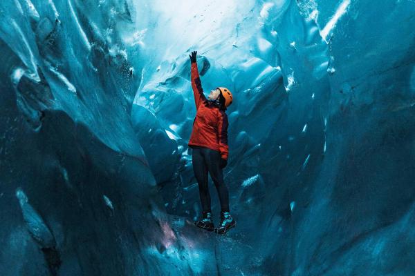 Girl climbing an ice cave in Iceland
