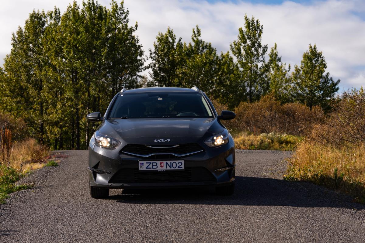 Vista frontal de un Kia Ceed familiar aparcado en una carretera asfaltada rodeada de árboles