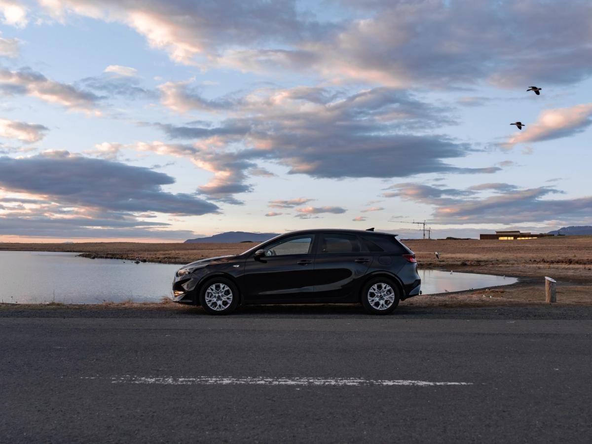 Pôr do sol à beira do lago Ceed Kia Ceed alugado na Islândia, estacionado junto a um lago ao pôr do sol