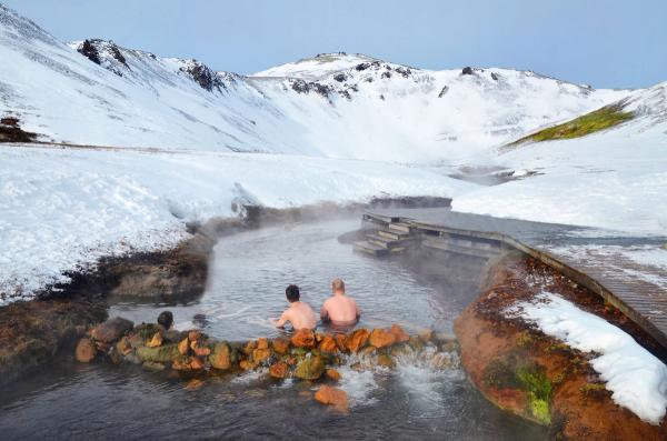 personas bañándose en un río caliente entre montañas nevadas