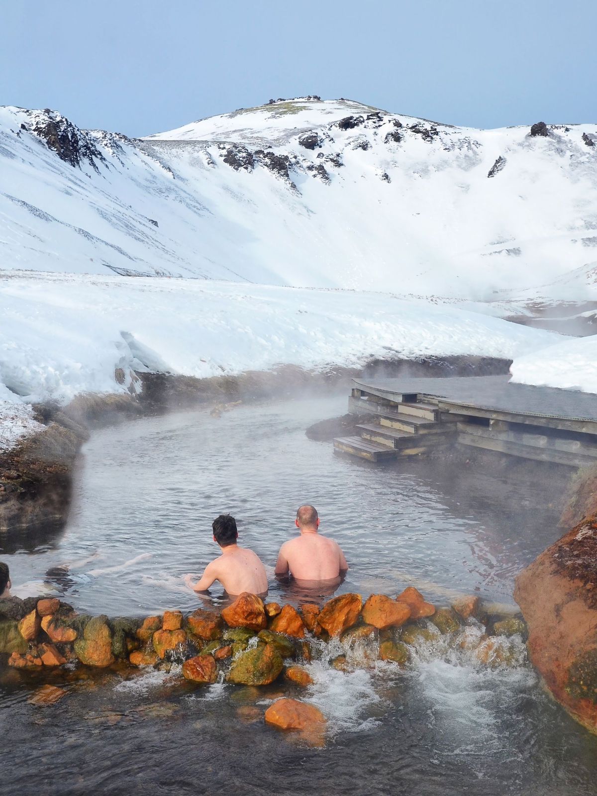 Hot Springs in South Iceland People sitting in Hot river in Iceland in winter snowy mountains
