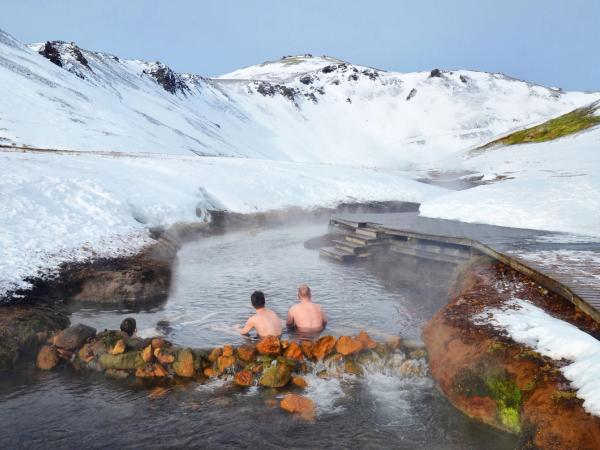 Gente dentro del "hot river" de Islandia rodeados de montañas nevadas