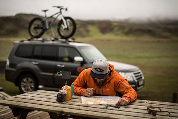 a man is sitting at a picnic table looking at a map .