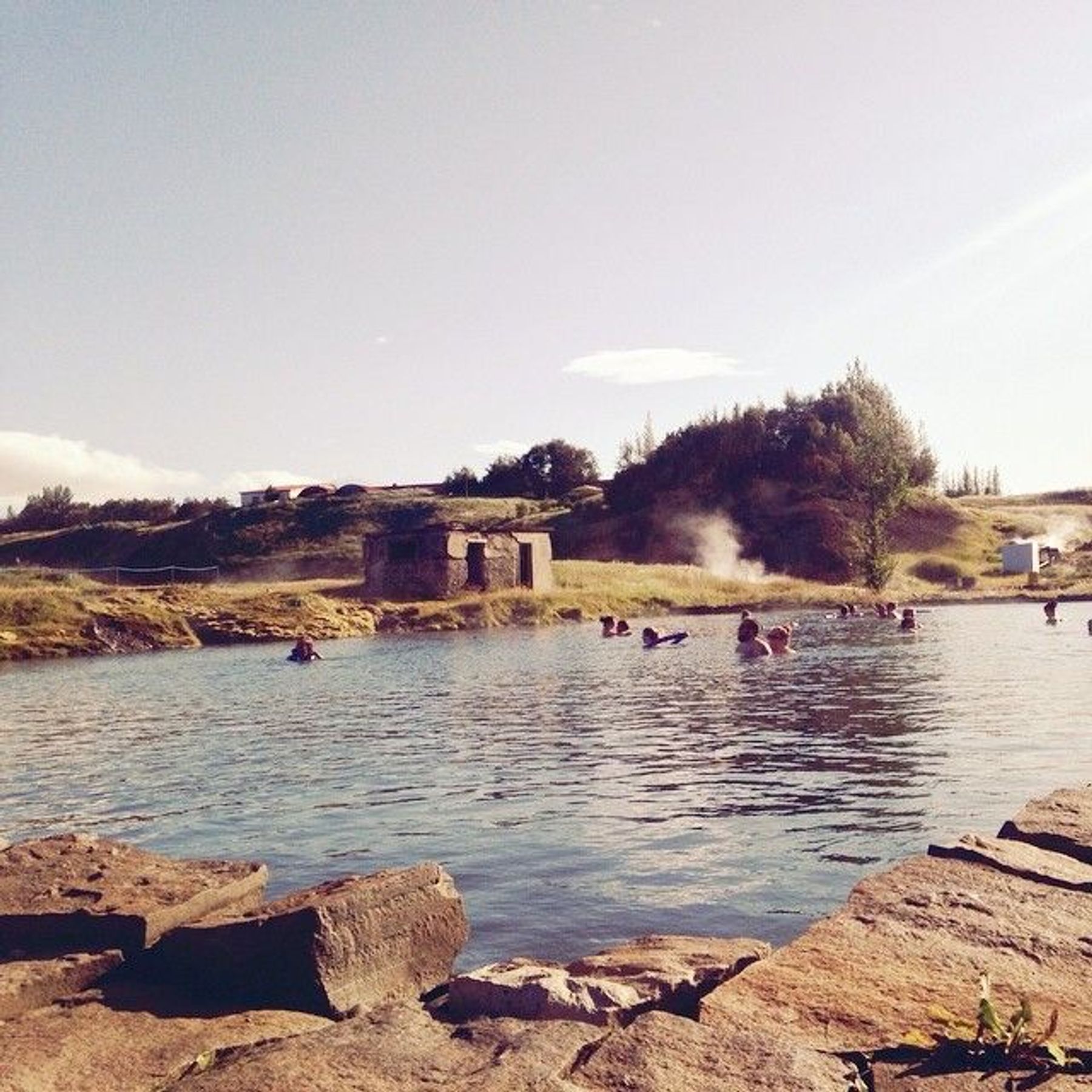 a group of people are swimming in a lake surrounded by rocks .