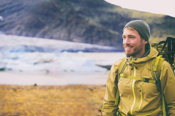 Smiling hiker with a glacier and mountains in the background.