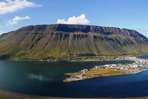 a panoramic view of a lake surrounded by mountains and the city of Ísafjörður