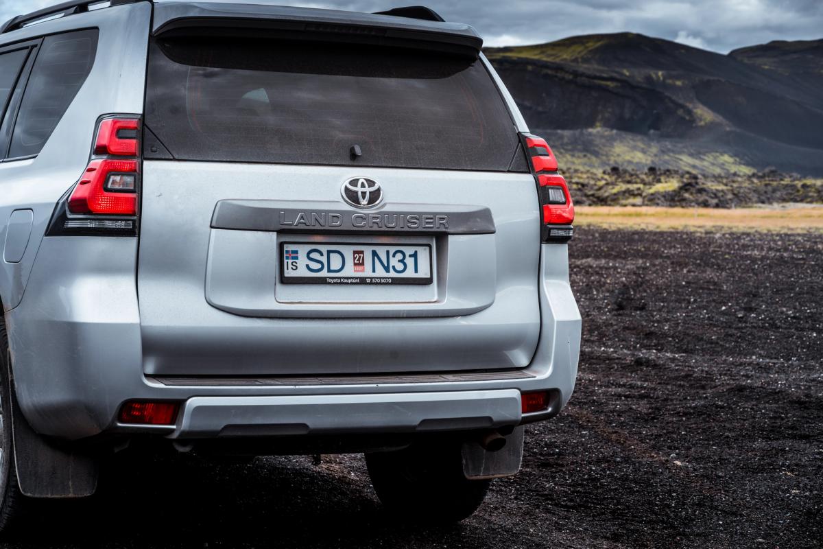 Toyota Land Cruiser rear tailgate close up with badge and rear lights on a gravel surface