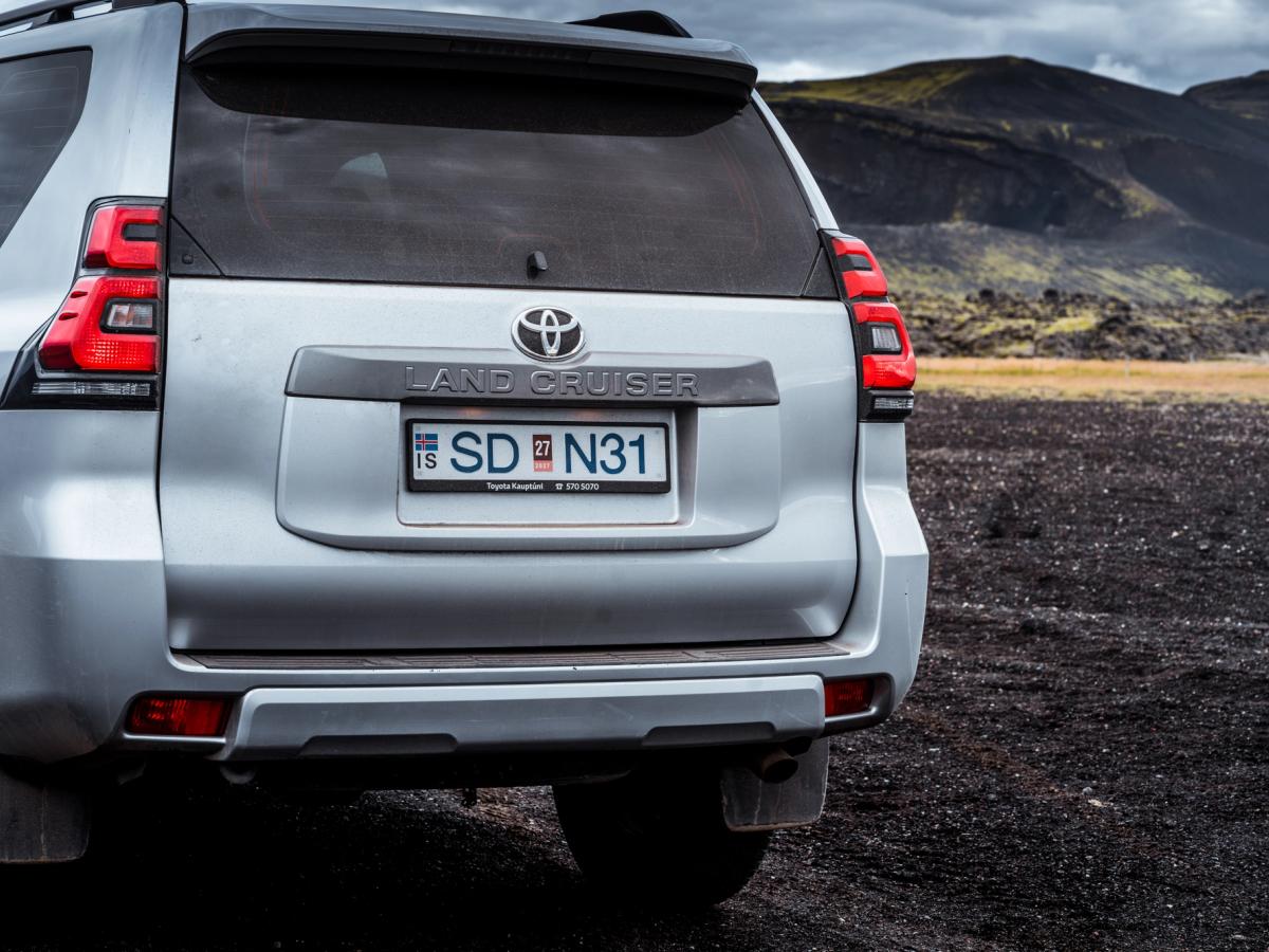 Detailansicht der Land-Cruiser-Heckklappe Nahaufnahme der Heckklappe eines Toyota Land Cruiser mit Emblem und Rückleuchten auf einem Schotterplatz