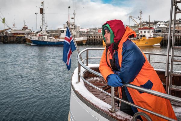photo of a fisherman particularly well covered, on his Icelandic boat in winter 