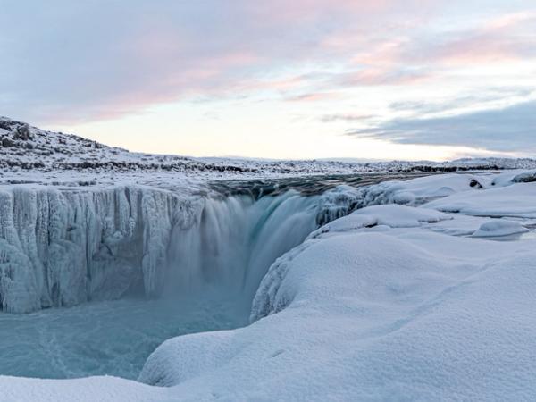 Una cascada atraviesa un paisaje invernal cubierto de nieve y hielo.