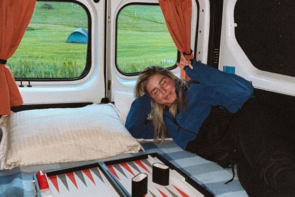 a woman is laying in the back of a van next to a board game in iceland.