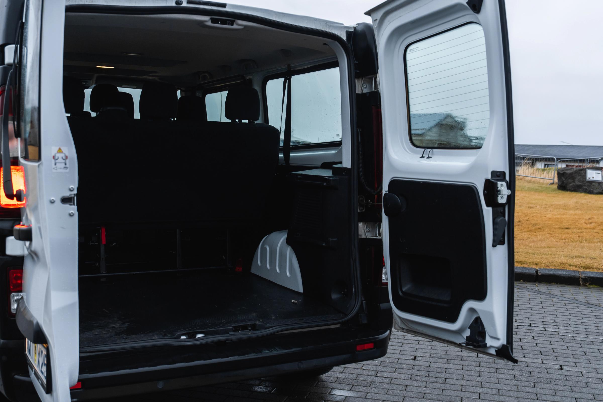 Vista trasera en ángulo de un monovolumen Renault Trafic con las puertas abiertas, mostrando los asientos y la zona de carga