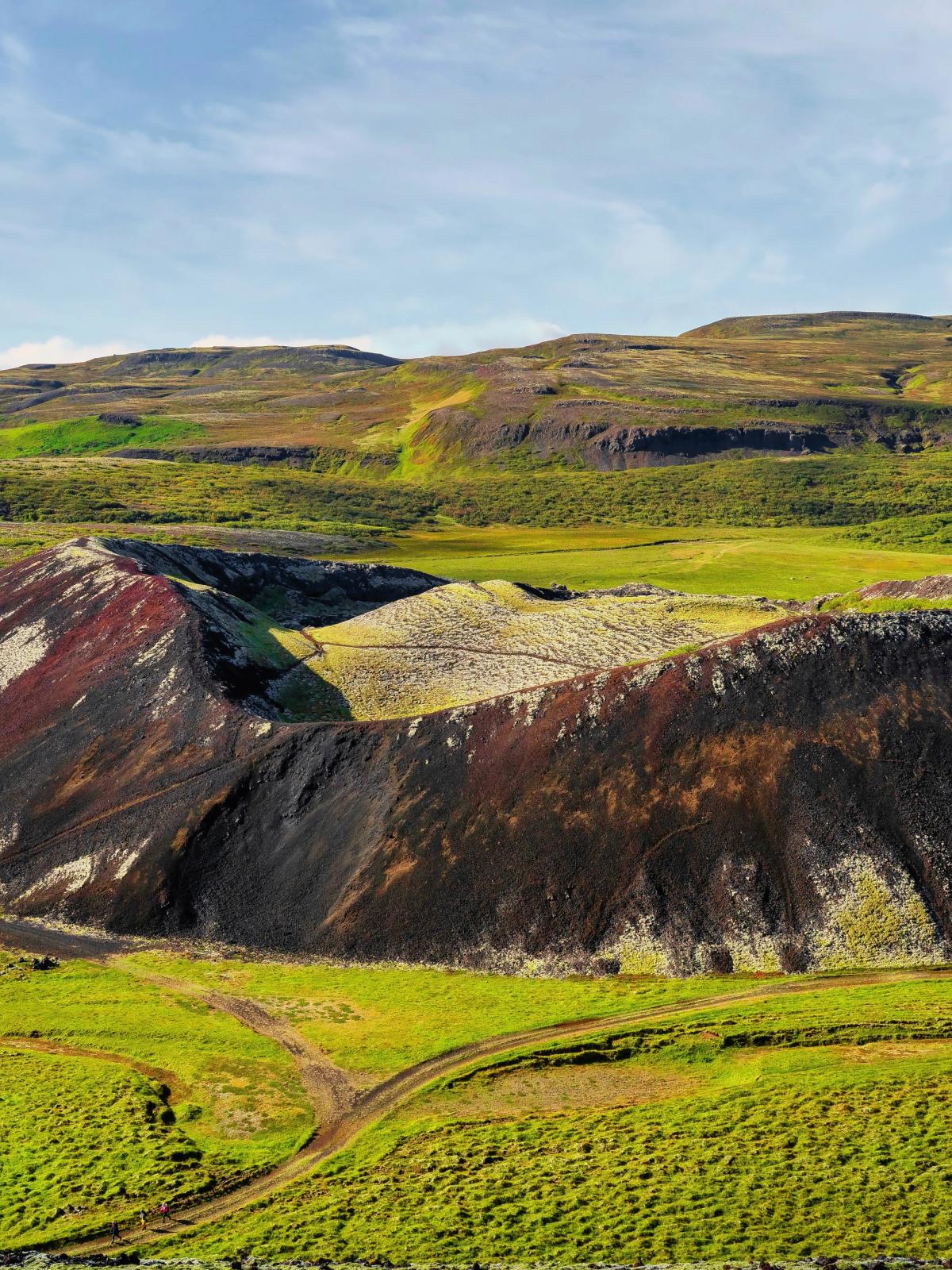 una vista aérea de un volcán colorido en medio de un campo verde .