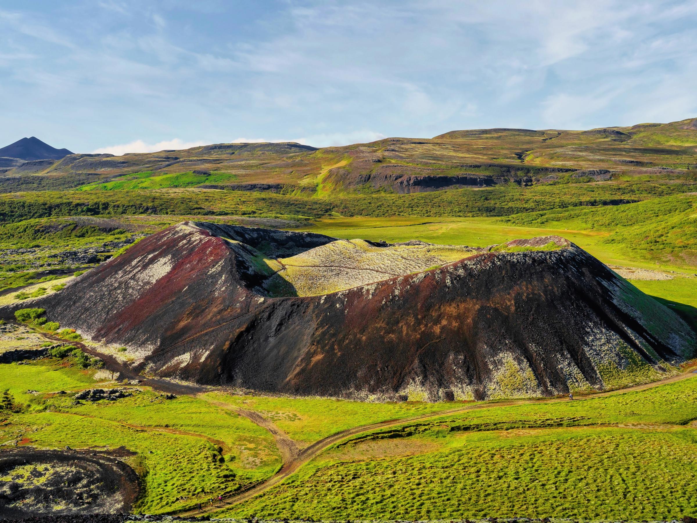 an aerial view of a colorful volcano in the middle of a green field .