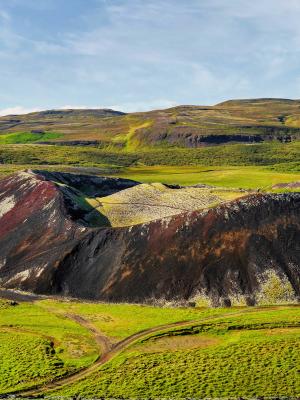 an aerial view of a colorful volcano in the middle of a green field .