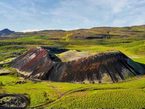 an aerial view of a colorful volcano in the middle of a green field .