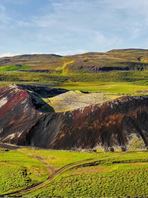 an aerial view of a colorful volcano in the middle of a green field .