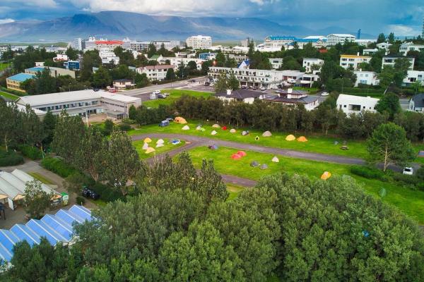 Imagen aérea de un camping con muchas tiendas de campañas rodeado de árboles y casas