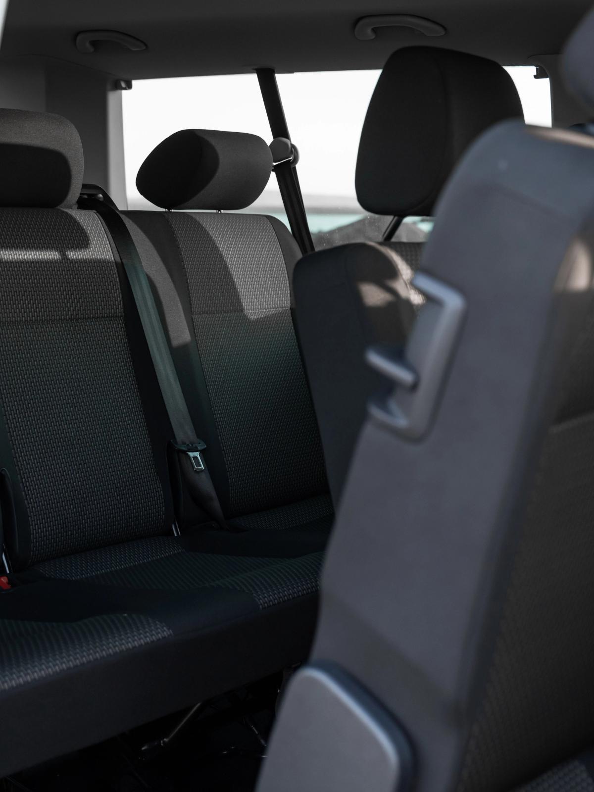 Interior of a vehicle with dark grey rear seats, one seat folded forward.