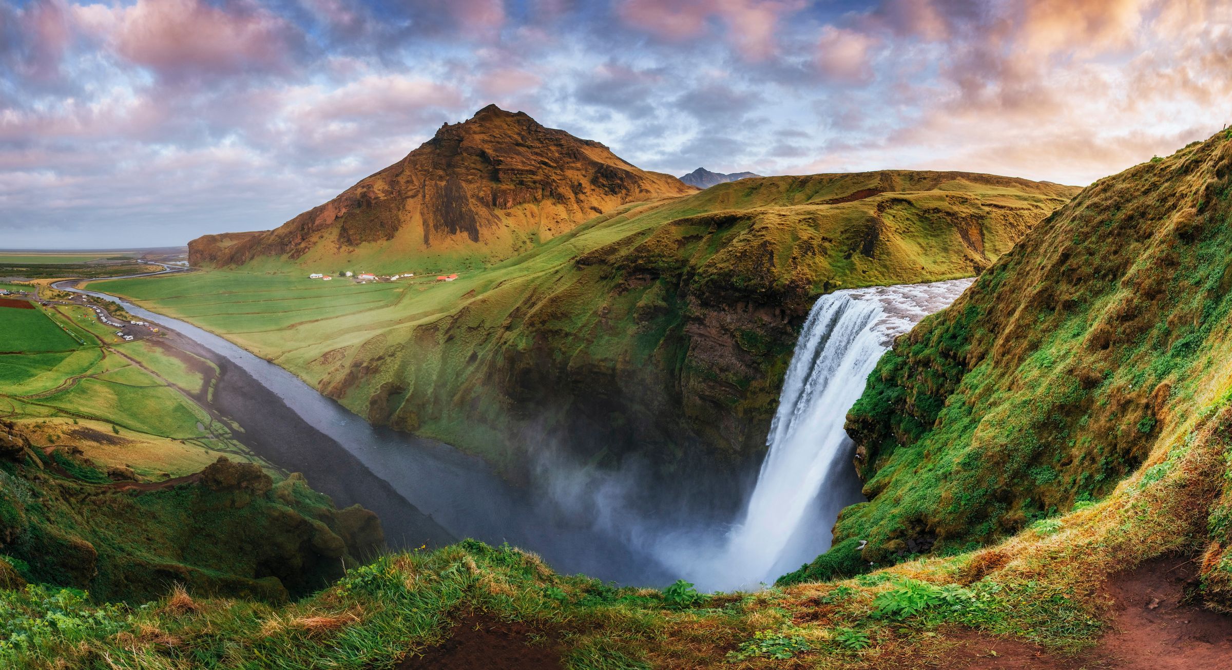 vista panorámica de un río y su cascada con una montan1a al fondo