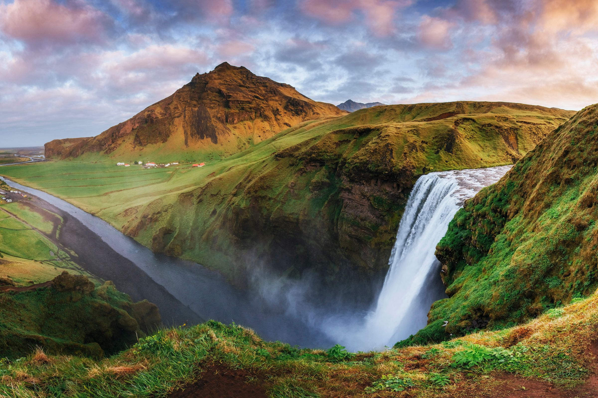 vista panorámica de un río y su cascada con una montan1a al fondo
