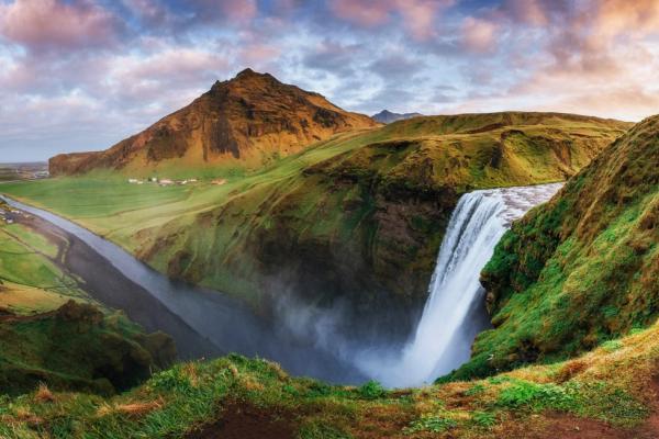 panoramic view of a river and a waterfall with a mountain on the background