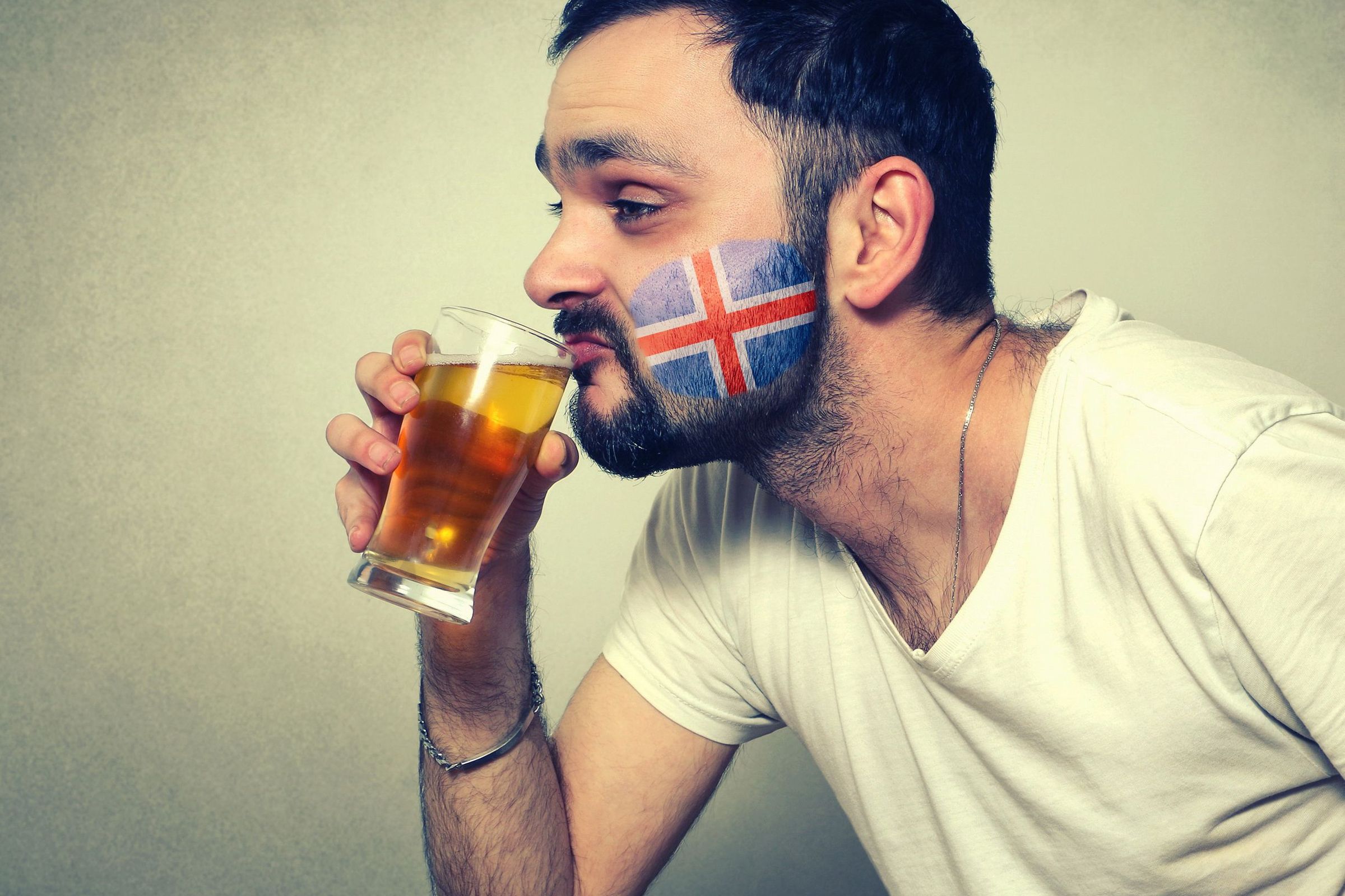 a man with a flag painted on his face is drinking a glass of beer .