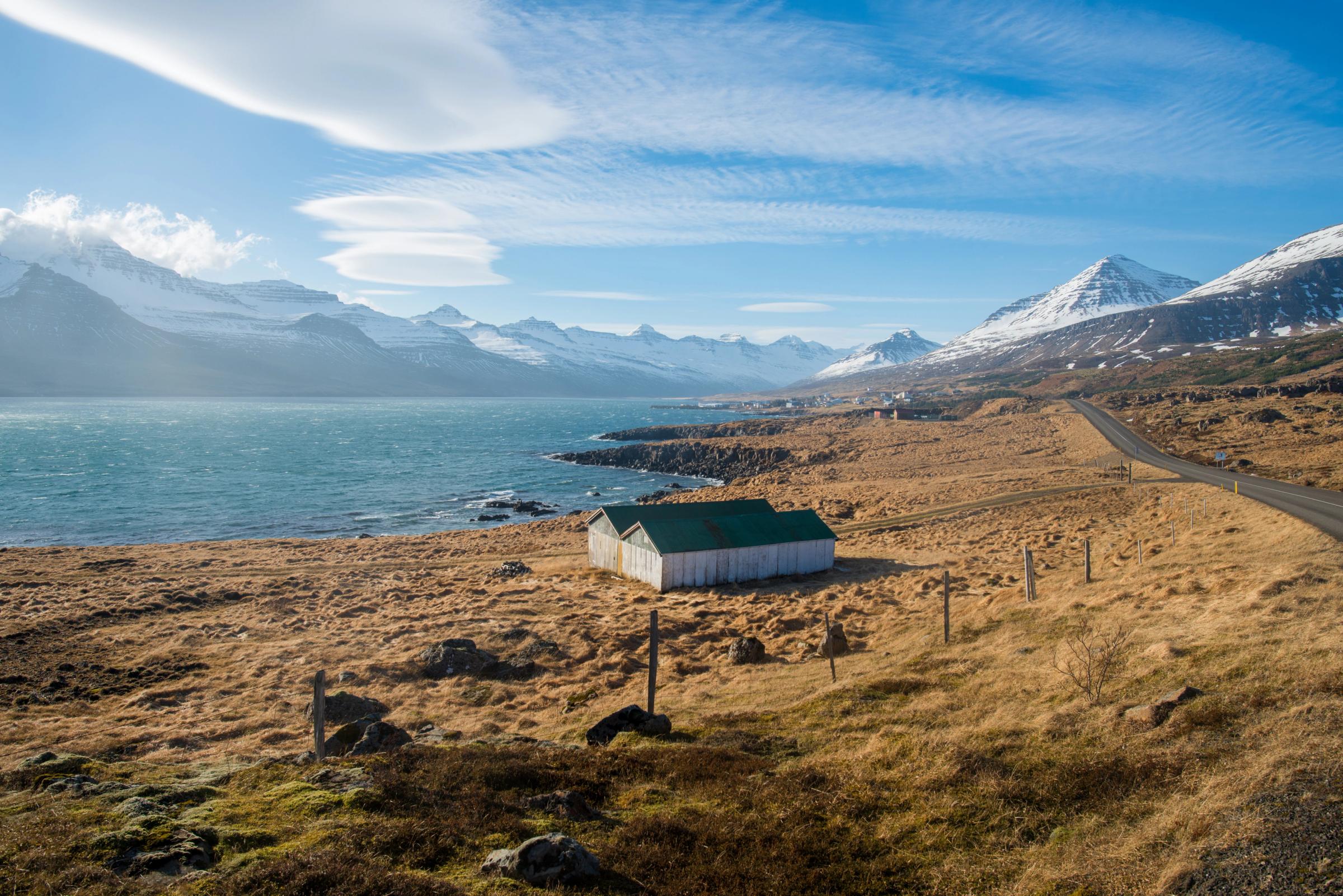 a landscape with a fiord and mountains covered by snow