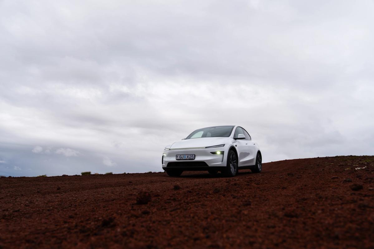 SUV eléctrico Tesla Model Y de alquiler en solitario en las tierras altas volcánicas rojizas de Islandia