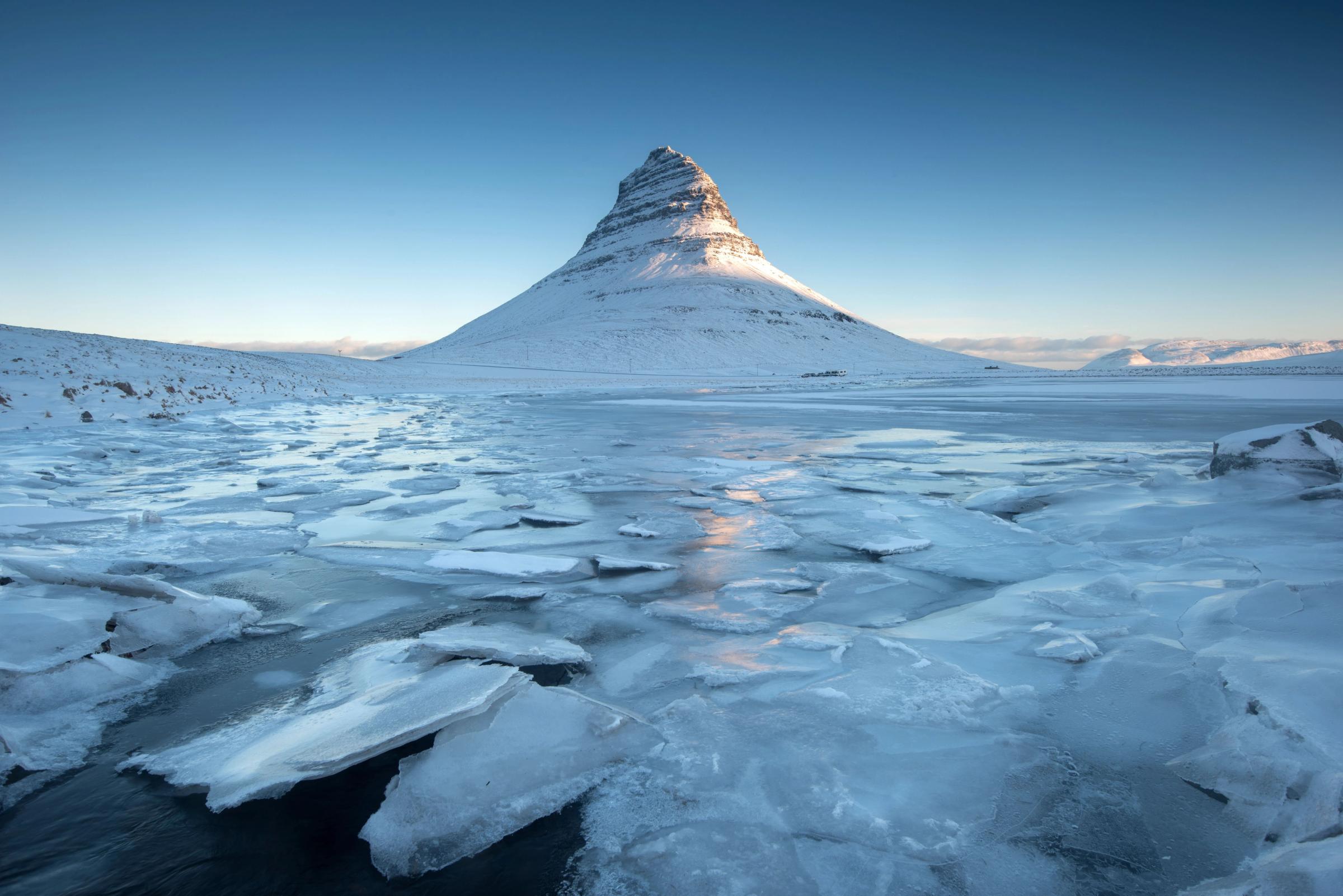 there is a mountain in the background and a lake covered in ice .