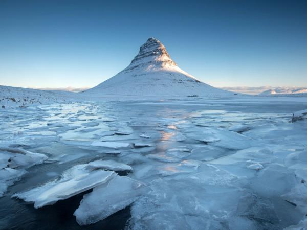 there is a mountain in the background and a lake covered in ice .