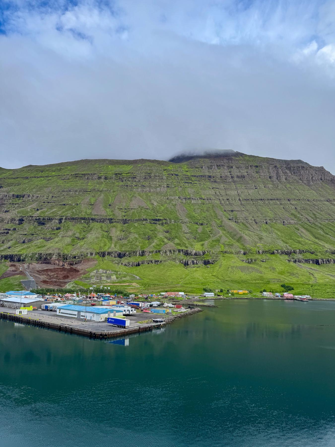 Aerial of a small town near the sea and a big green mountain in the background