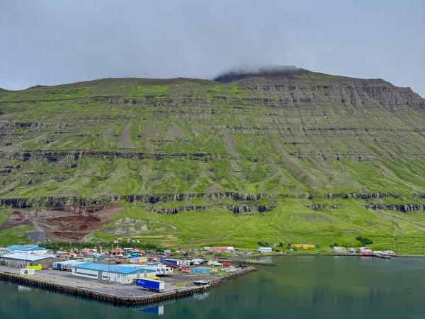 Aerial of a small town near the sea and a big green mountain in the background