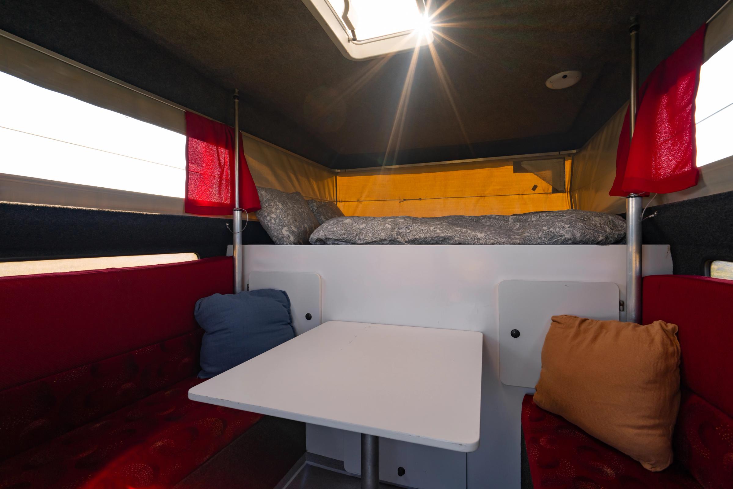 Dinette And Table Dinette with table and red bench seats below the over-cab bed and roof skylight