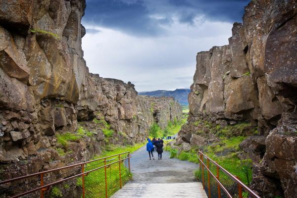 a couple of people are walking across a bridge in the middle of a canyon .
